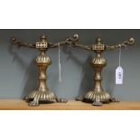 A pair of aesthetic movement brass fire dogs with decoratively cast tool rests,
