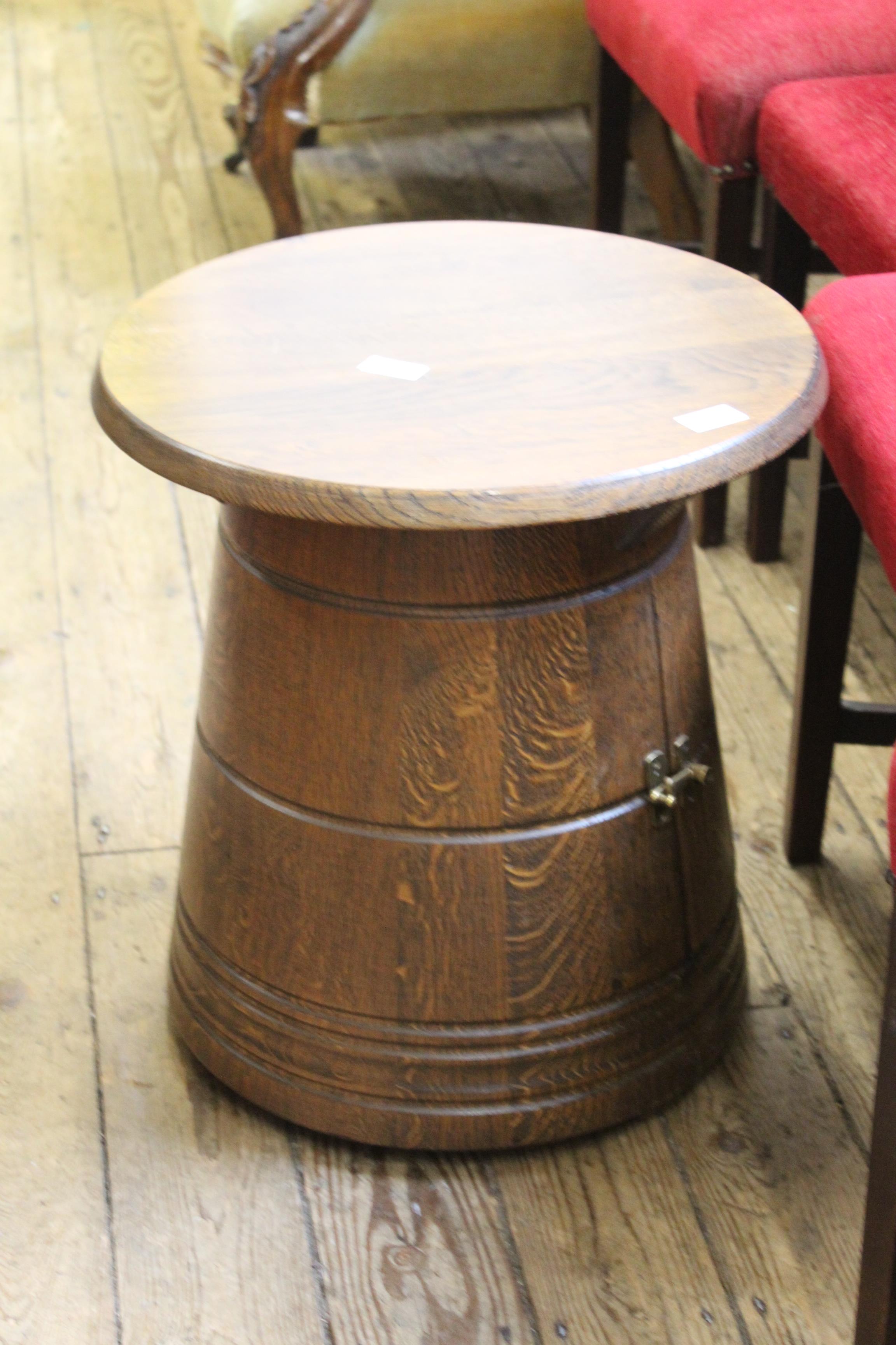 An occasional table in the form of a small oak barrel with small cupboard below