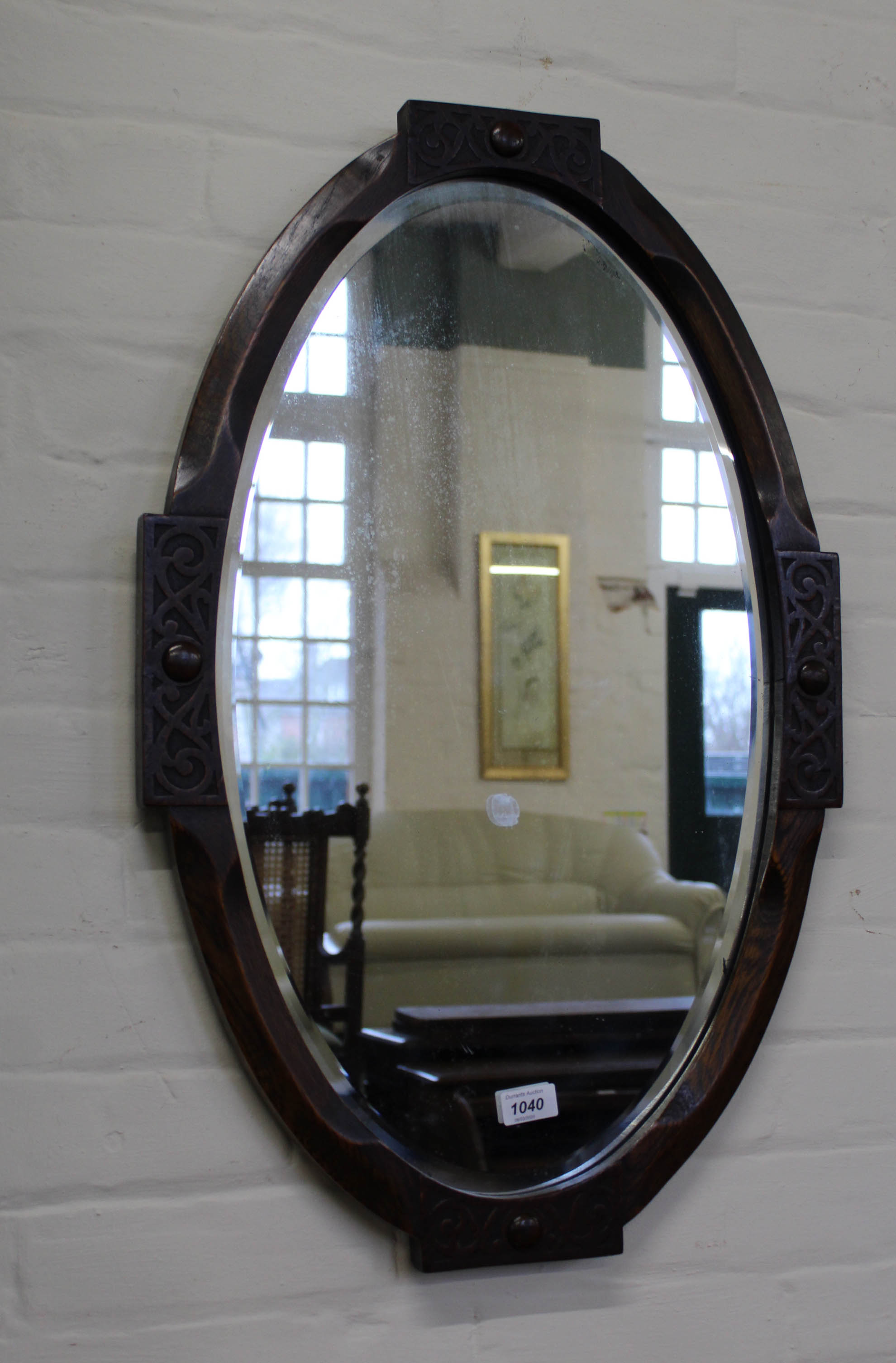 A carved oak oval bevelled mirror