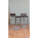 A pair of retro brown leather and steel swivelling bar stools