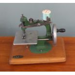 A Grain miniature sewing machine on wood plinth base