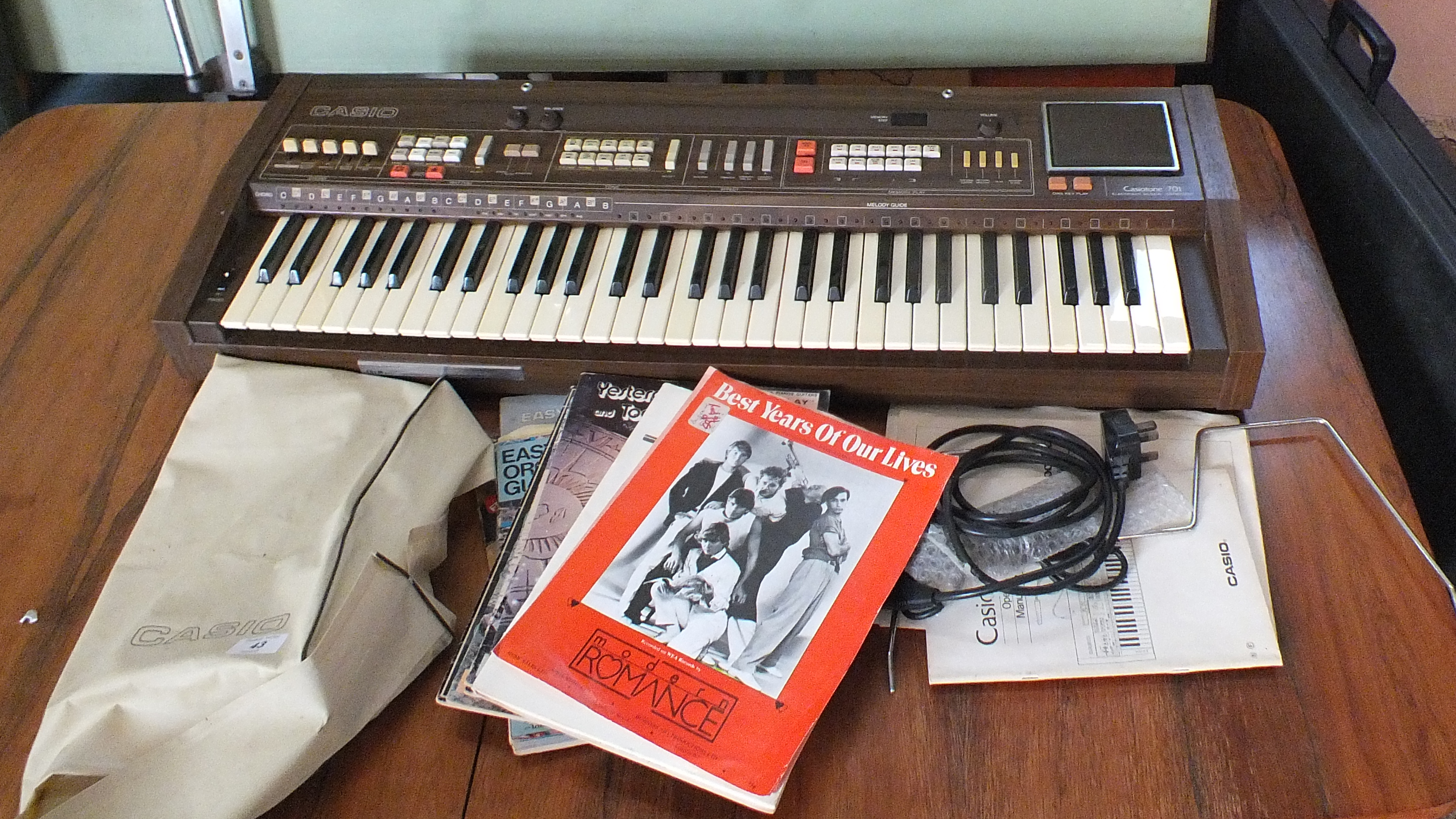 A Casiotone 701 1980's keyboard with manual, music stand and a quantity of sheet music.