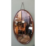 An oval framed bevelled wall mirror