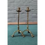 A pair of Arts and Crafts barley twist brass candlesticks with drip trays and tripod legs,