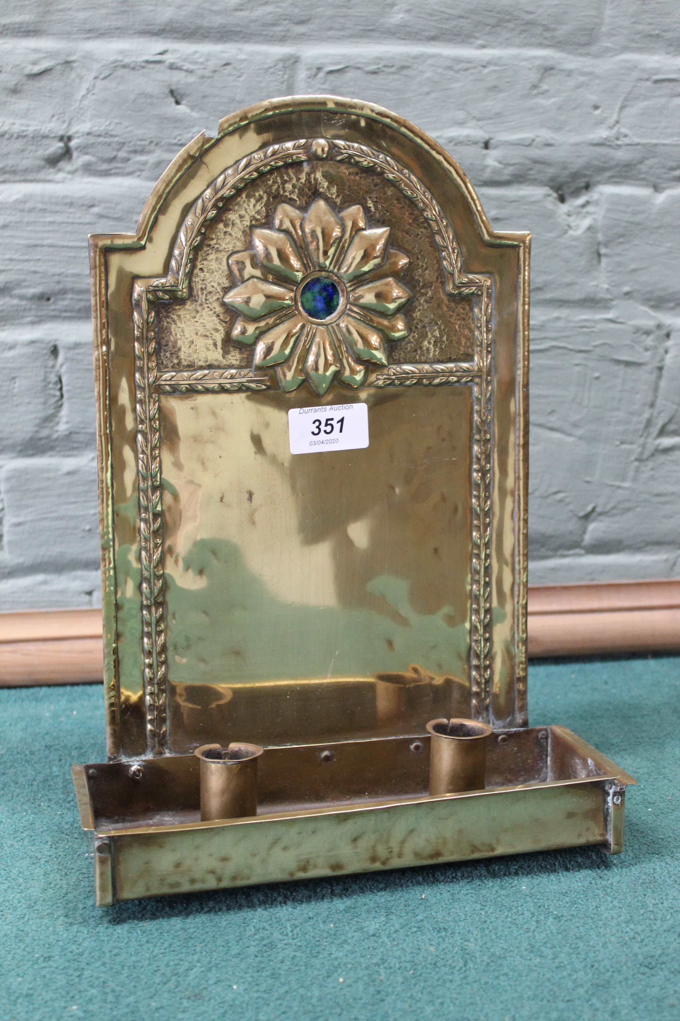 An Arts and Crafts twin socket hanging brass wall sconce with embossed back plate having ruskin