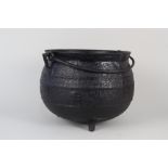 A heavy antique bulbous cast iron cauldron with ribbed decoration,