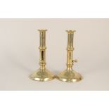 A pair of early 18th Century side ejector brass candlesticks on domed circular bases,