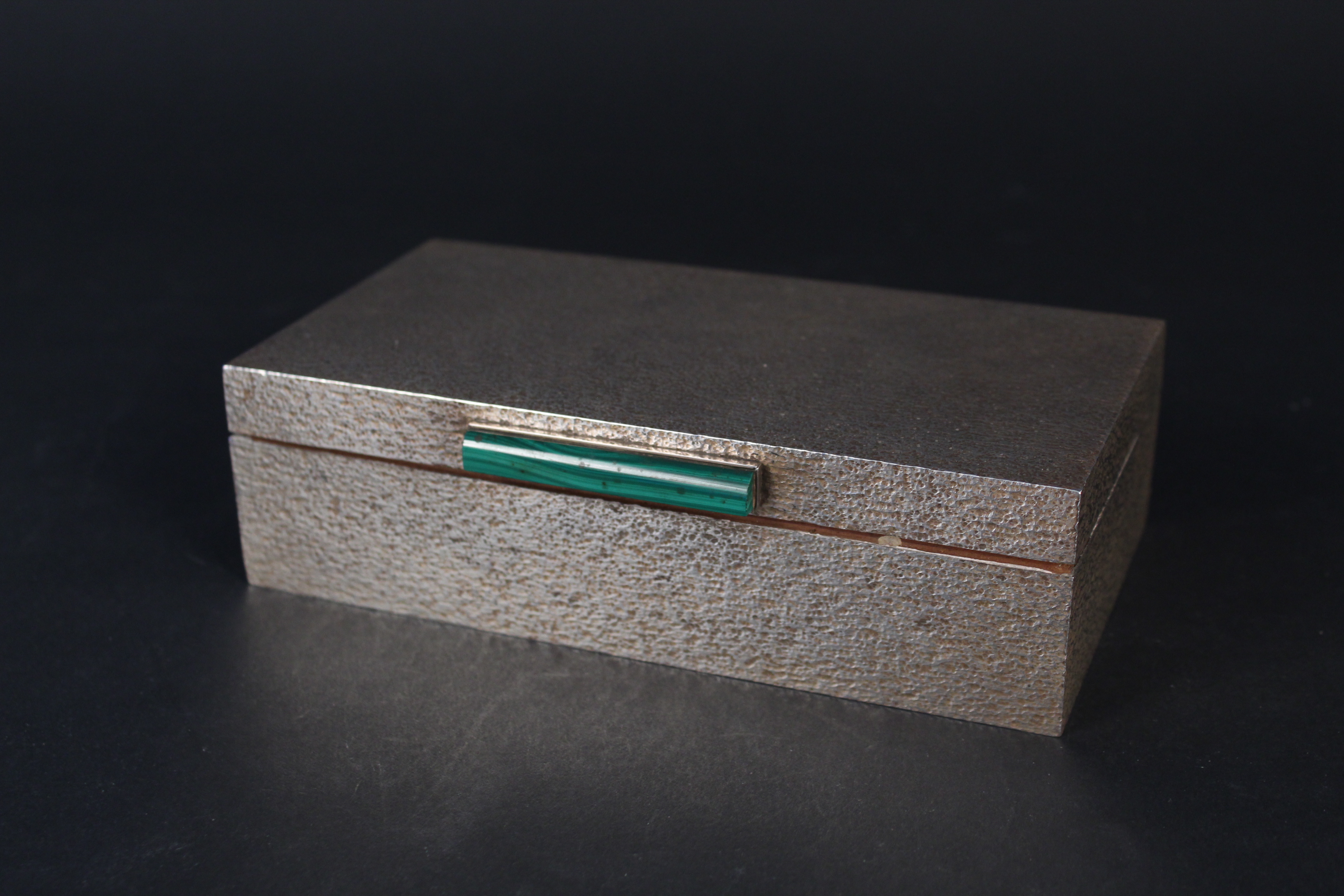 A large silver cigarette box with bark effect decoration and malachite set clasp,