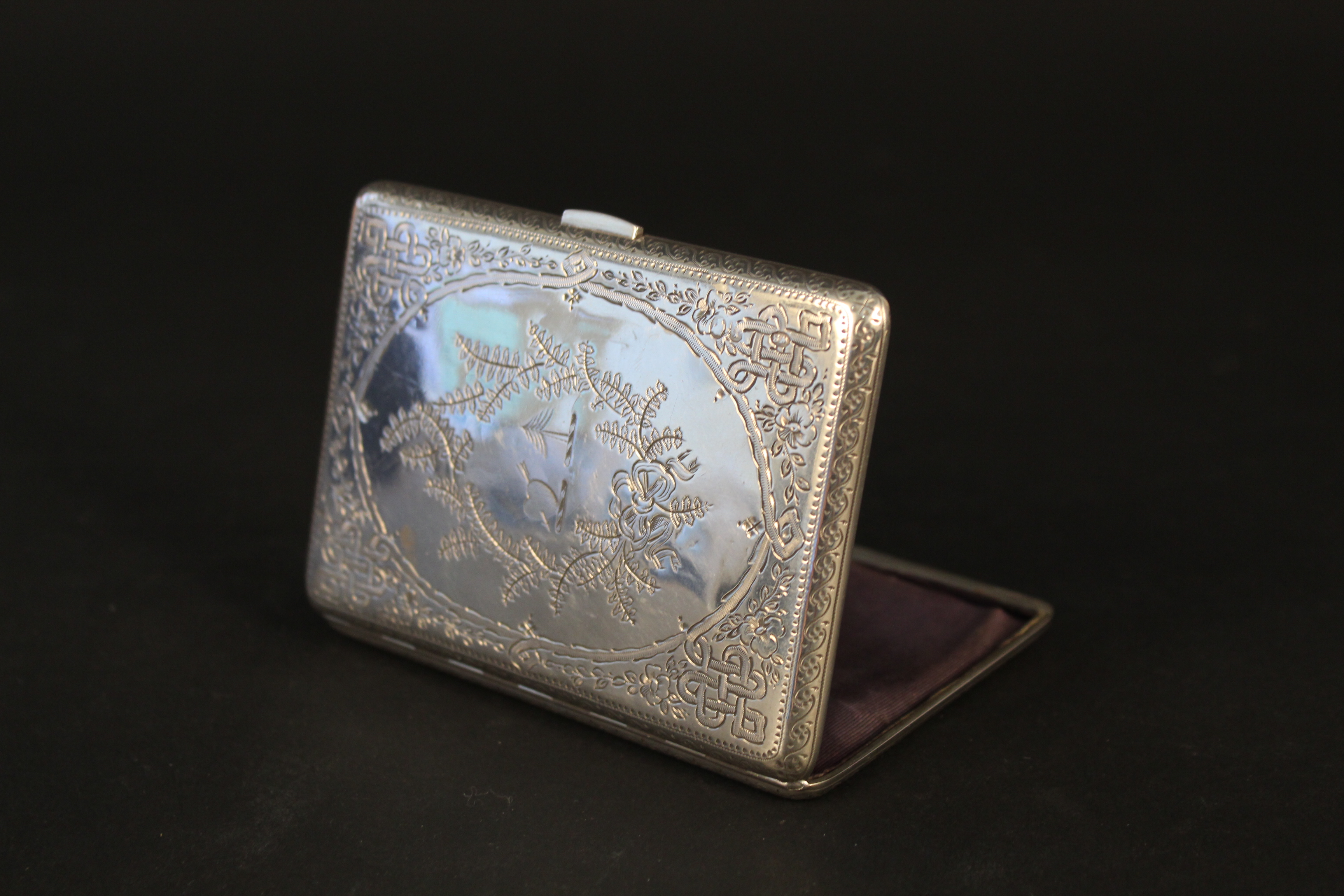 A silver card case with lined interior, engraved decoration to front and back,