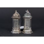 A pair of Carrington & Co silver pepperettes of hexagonal form (one has corrosion to lid),