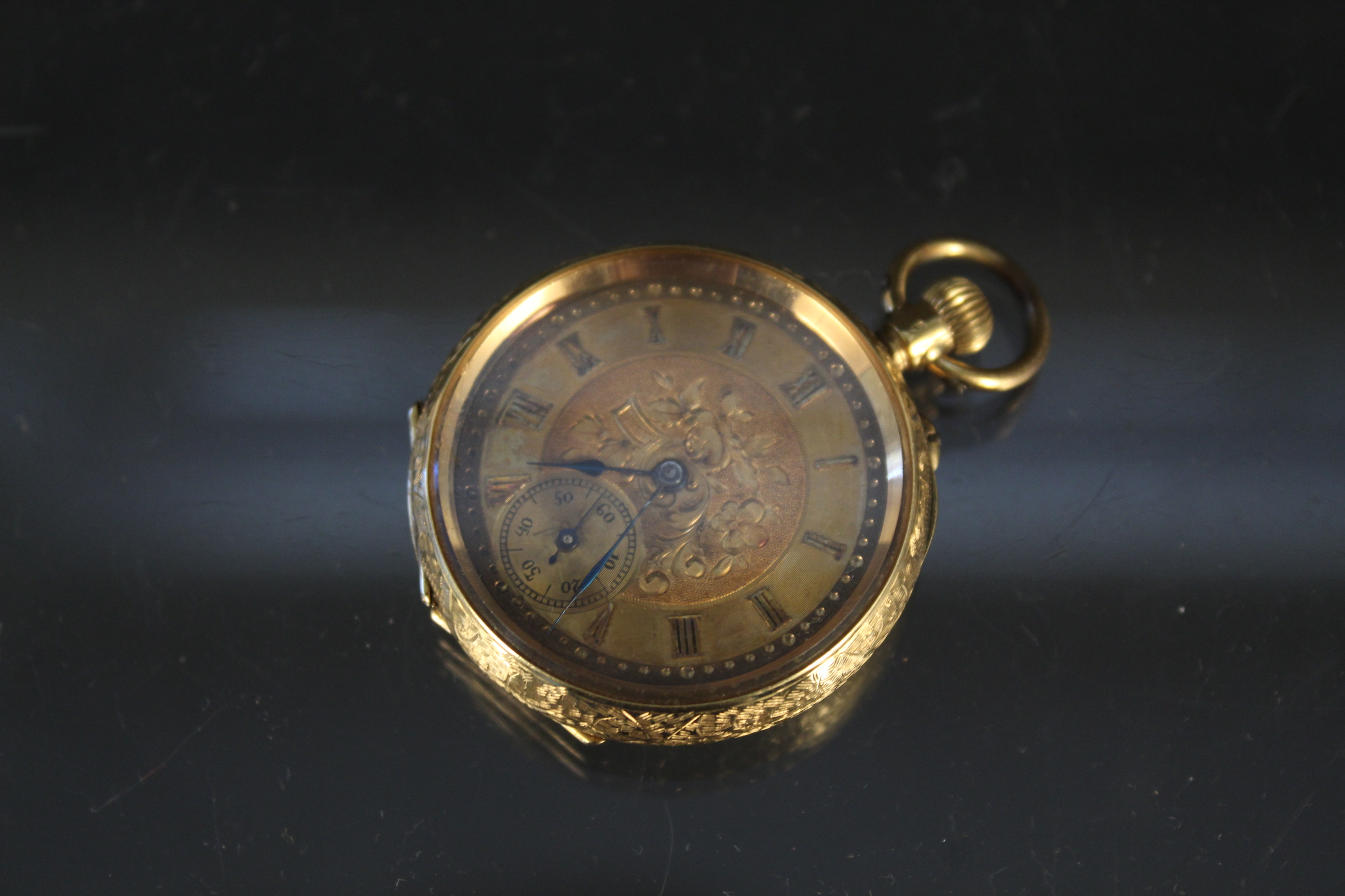 A 14ct gold continental fob watch with foliate decoration (metal dust cover)