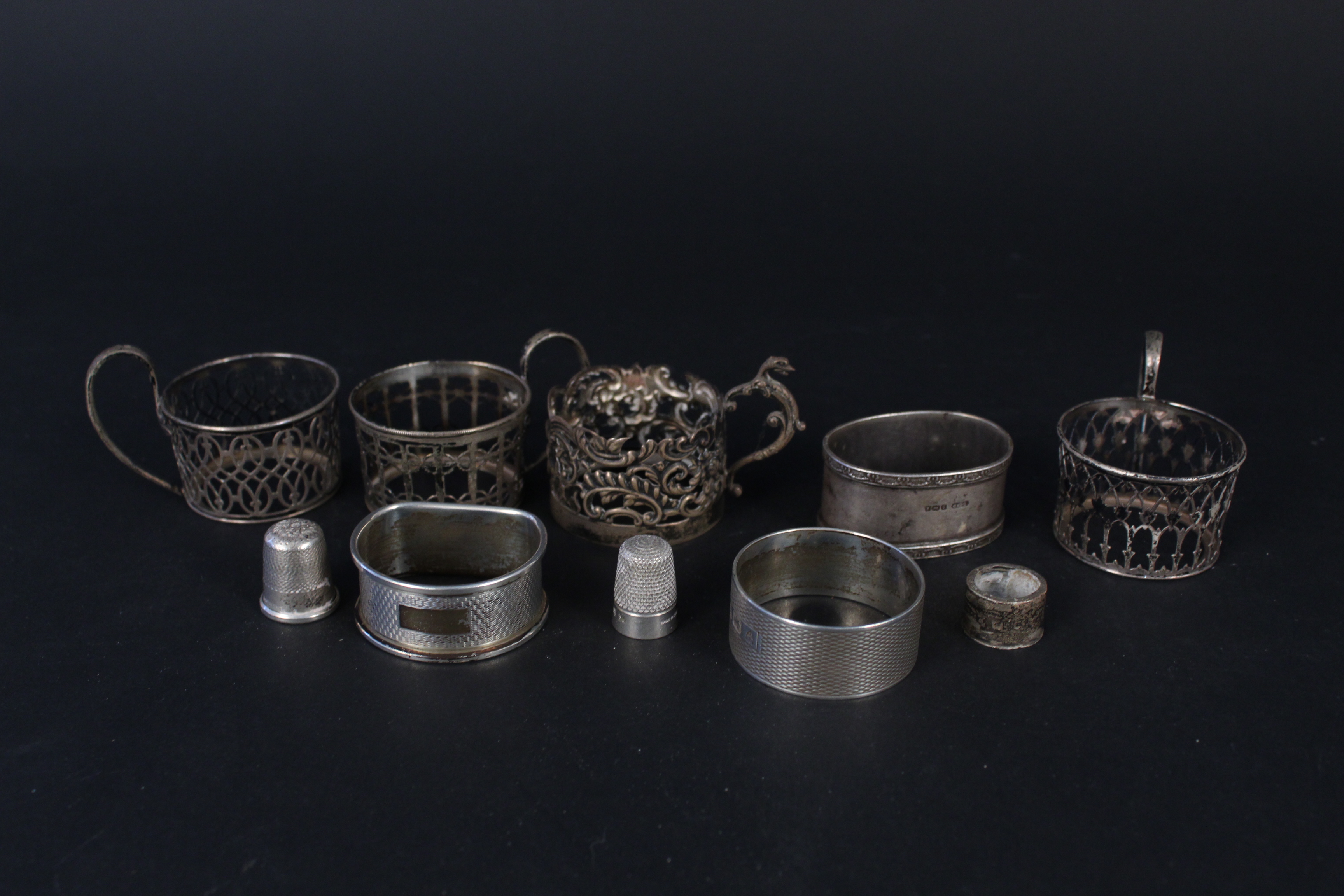 Three silver napkin rings, four silver cup holders (no glass) plus two silver thimbles,