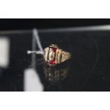 A 10K college style ring set with red stone, black enamel to shoulders with date 1953,