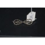 A white metal diamond set brooch of symmetrical design,