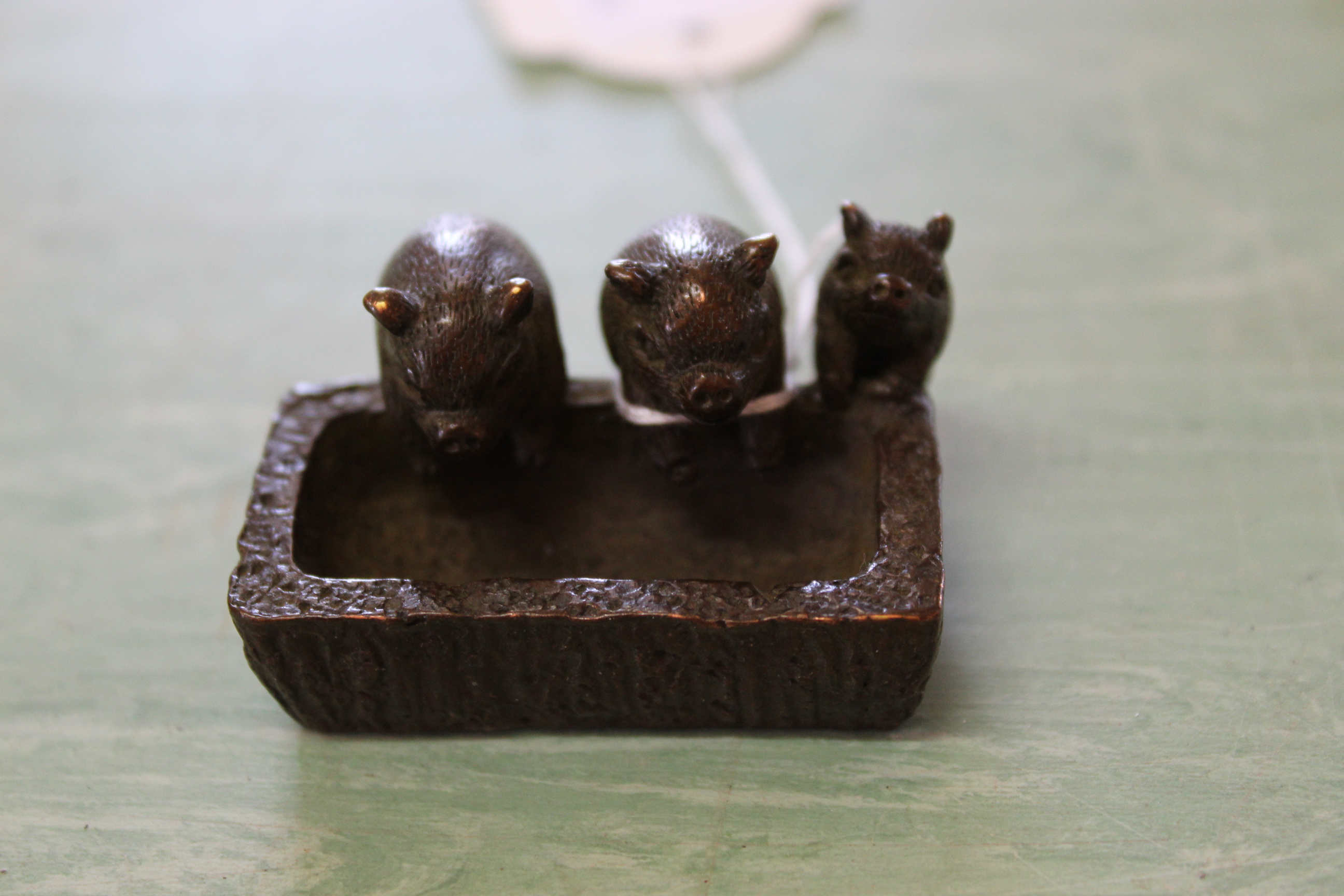 A small bronze of three pigs at a trough,