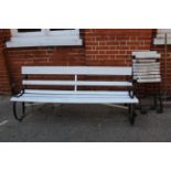 A black iron framed and white wood painted garden bench and two metal and wood slatted folding