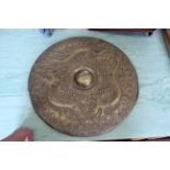 An oriental circular bronze shield with central raised boss with dragons, deer and fish,