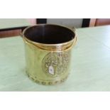 A heavy 19th Century brass log bucket with heraldic crest and swing handle,