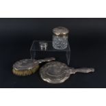 A three piece silver dressing table set together with an ornately embossed silver pill box