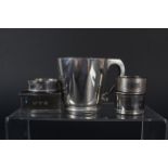 A small silver mug with engraved initials plus four various silver napkin rings (two engraved with