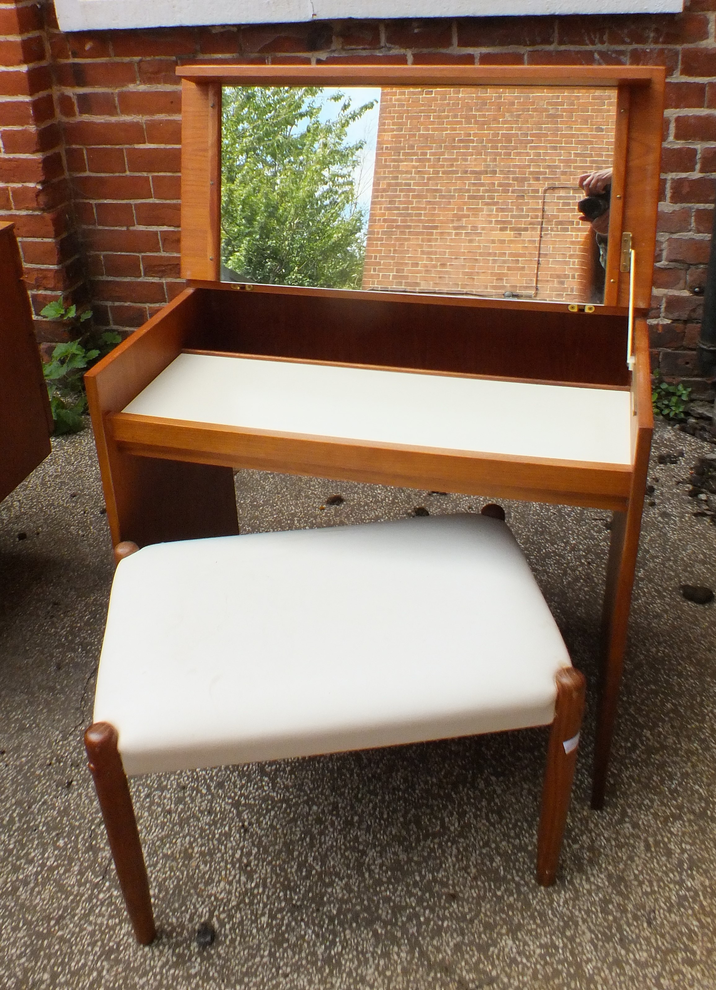 A 1970's teak style dressing table with lifting top with white leatherette covered stool on tapered