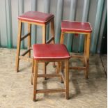 Three red leather topped kitchen stools in different heights