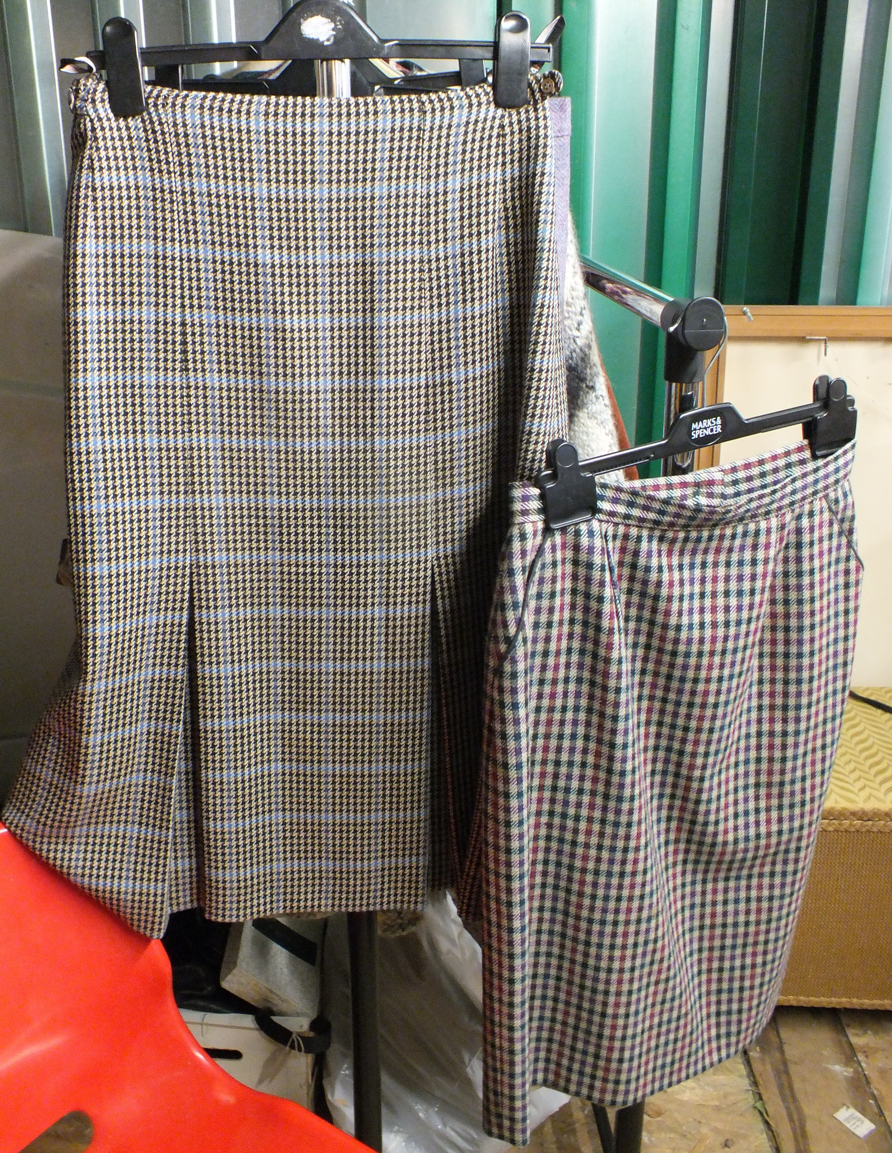 An assortment of vintage women's clothing including two checked pencil skirts, knitted cardigan,