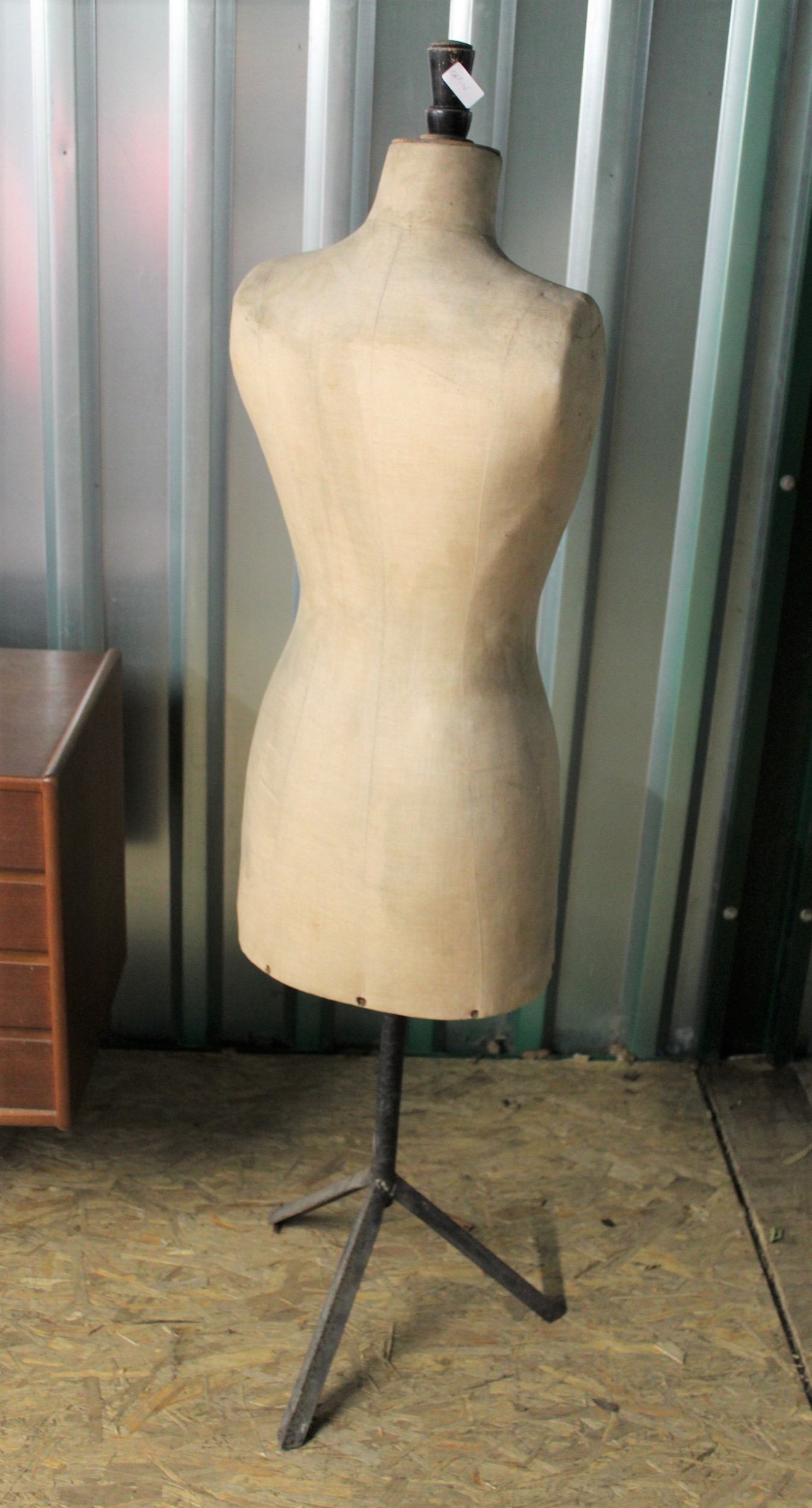 A vintage mannequin or tailor's dummy on black metal tripod base