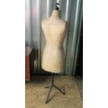 A vintage mannequin or tailor's dummy on black metal tripod base