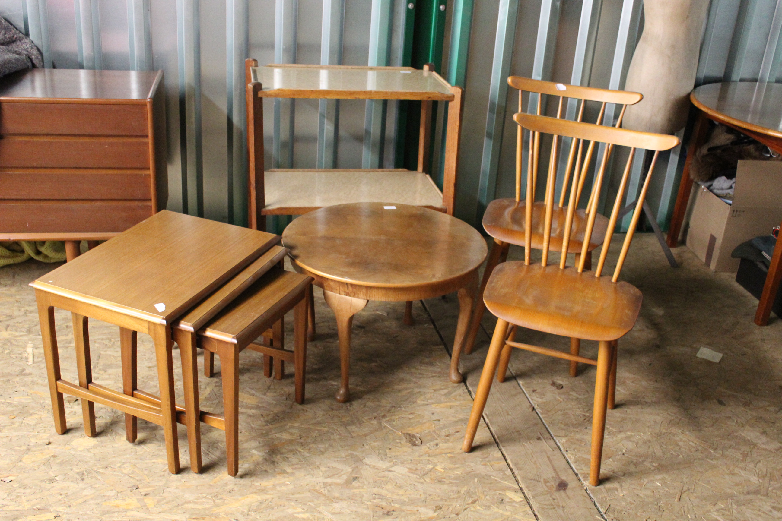 A collection of vintage wooden furniture including a nest of tables, two kitchen chairs,