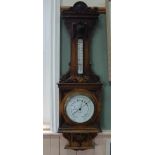 An Edwardian oak wall barometer with profusely carved case with heraldic shields and carved eagle