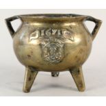 A heavy antique twin lug handled bronze cauldron with raised family crest,