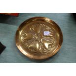 An Arts and Crafts Keswick School circular brass dish embossed with stylised tulips and stamped