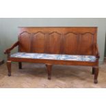 An oak George III style settle, with a five panelled back, standing on cabriole legs,
