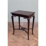 An Edwardian mahogany swivel top games table on cabriole legs and shaped under tier,