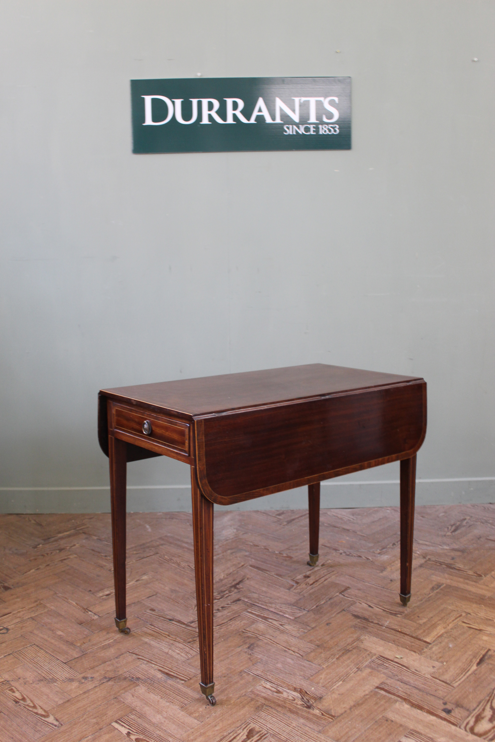 An early 19th Century mahogany inlaid Pembroke table on square tapered legs and brass box castors,