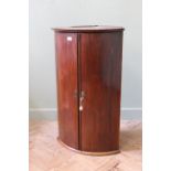 An early 19th Century mahogany bow fronted hanging corner cupboard,