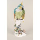 A 19th Century Dresden marked Macaw parrot perching on a branch with a small mouse at his feet,