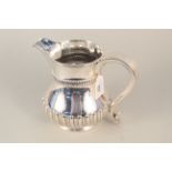 A silver water jug of half fluted design (dented),