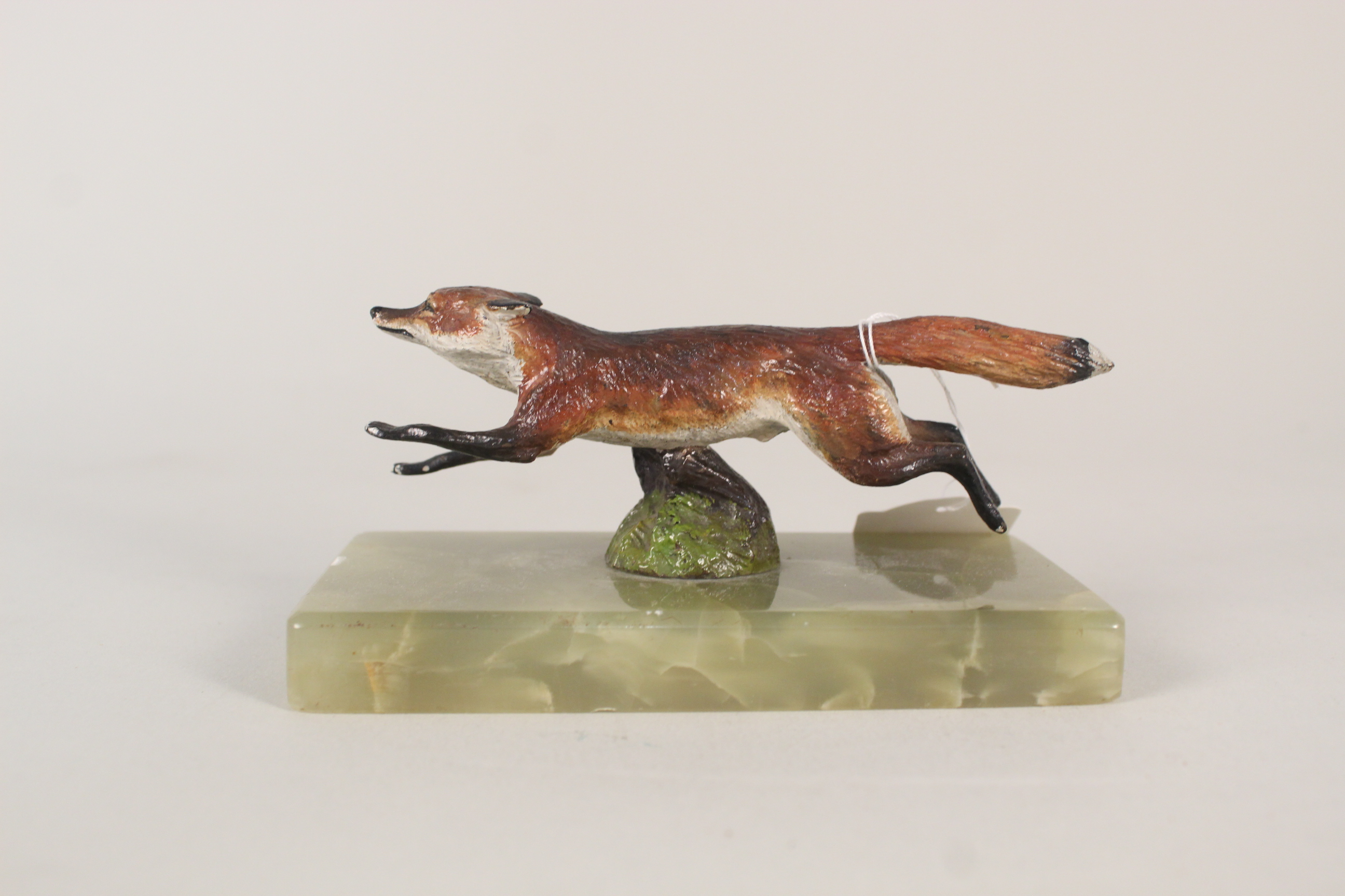 A cold painted bronze figure of a running fox on onyx base