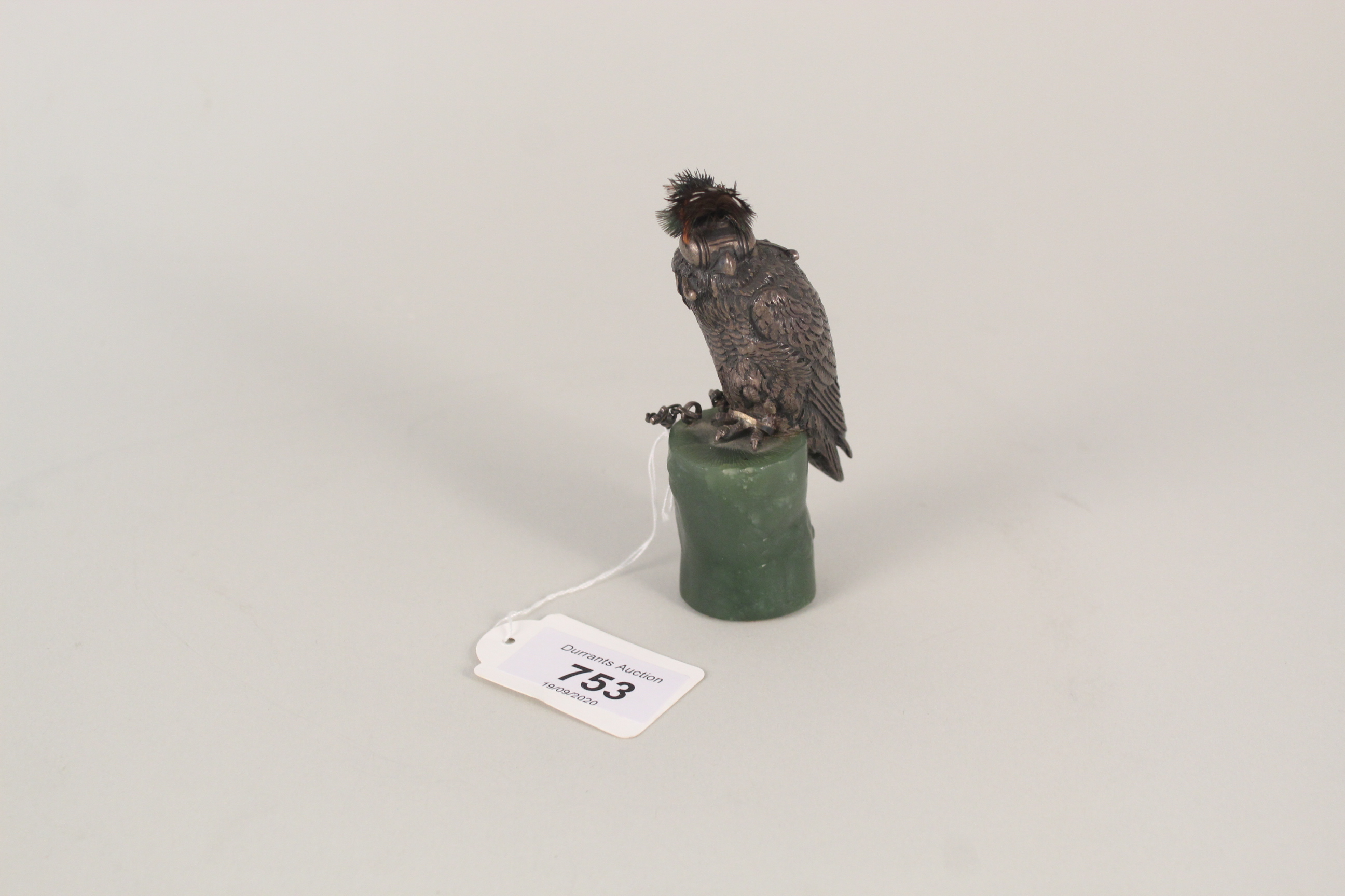 A silver model of a hawk with real feathers on top, mounted on green stone base hallmarked London,