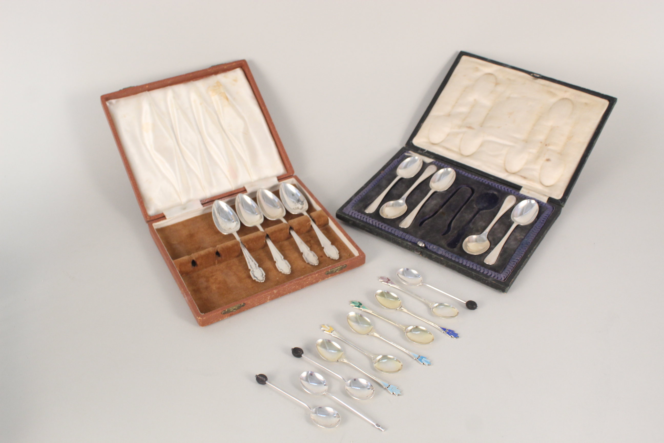 A collection of silver spoons including a set of six enamelled teaspoons (two are damaged),