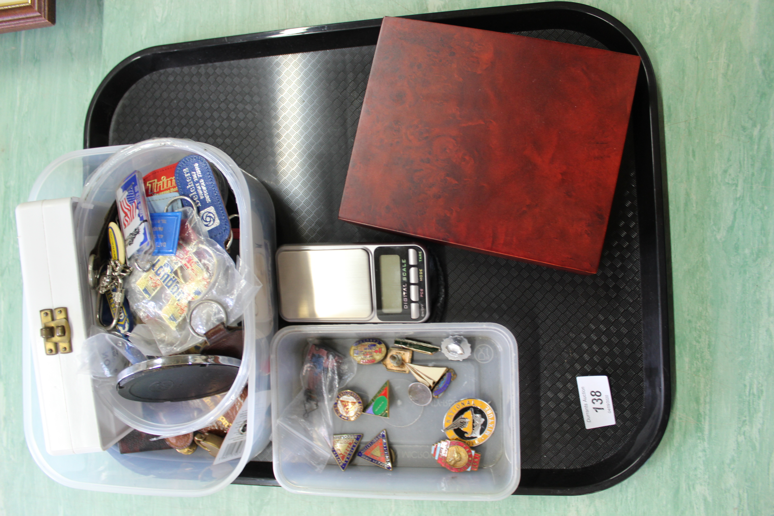 A tray with a tub of collectors badges, a tub of key rings,