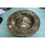 An Arts and Crafts brass alms dish with central boss and embossed decoration,