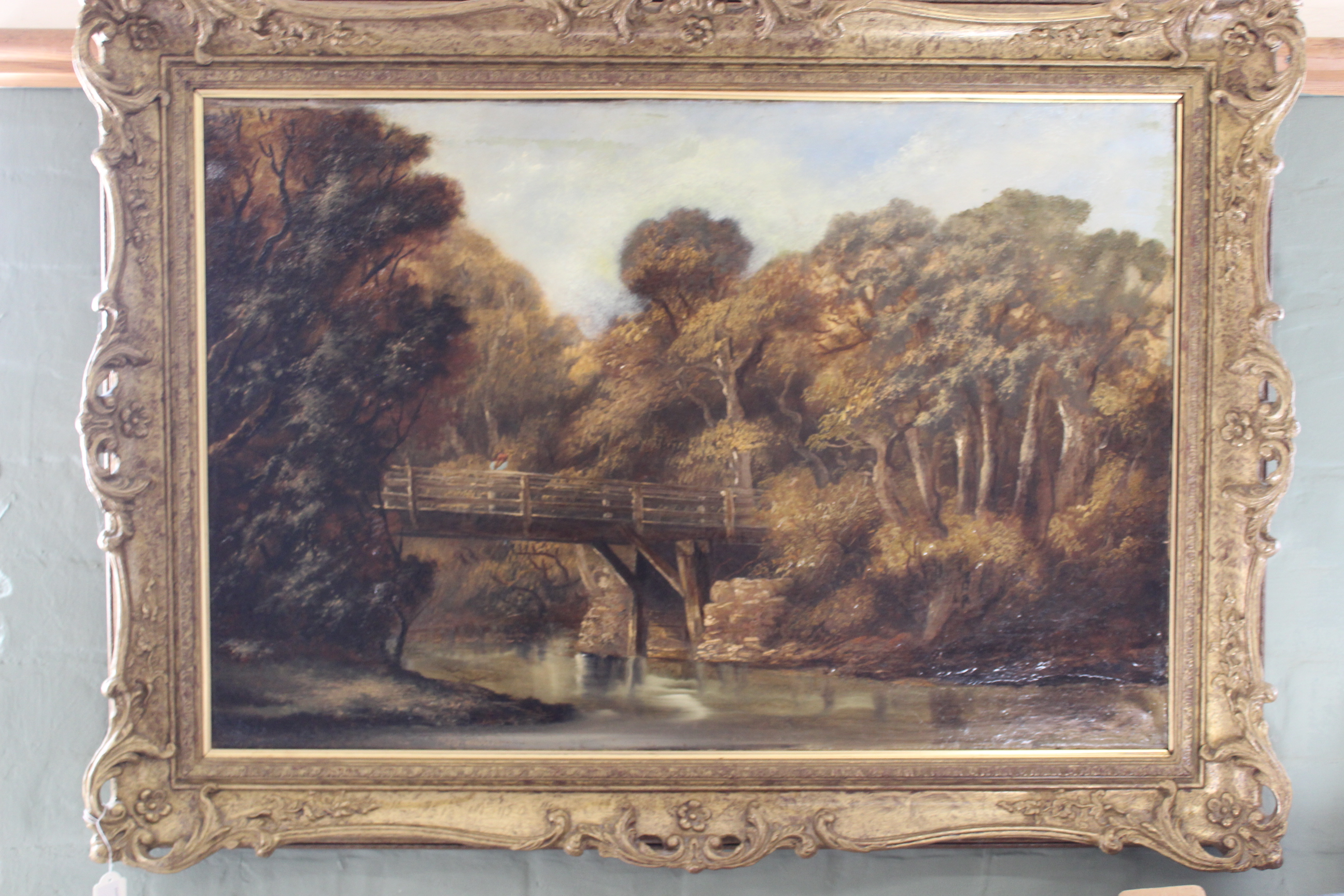 An oil painting of a rural scene, bridge over river, unsigned in gilt frame,