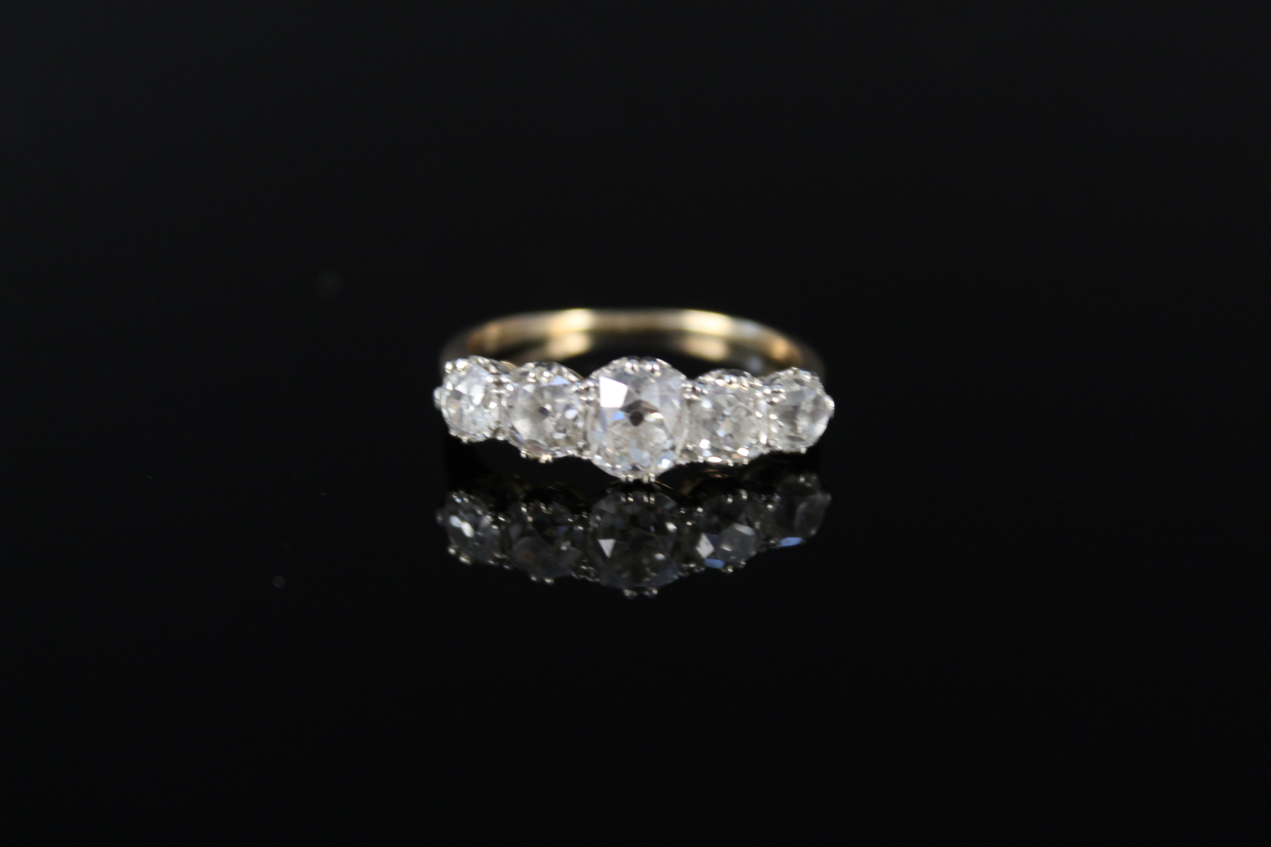 An impressive five stone diamond ring, the graduating old cut diamonds claw mounted in white metal,