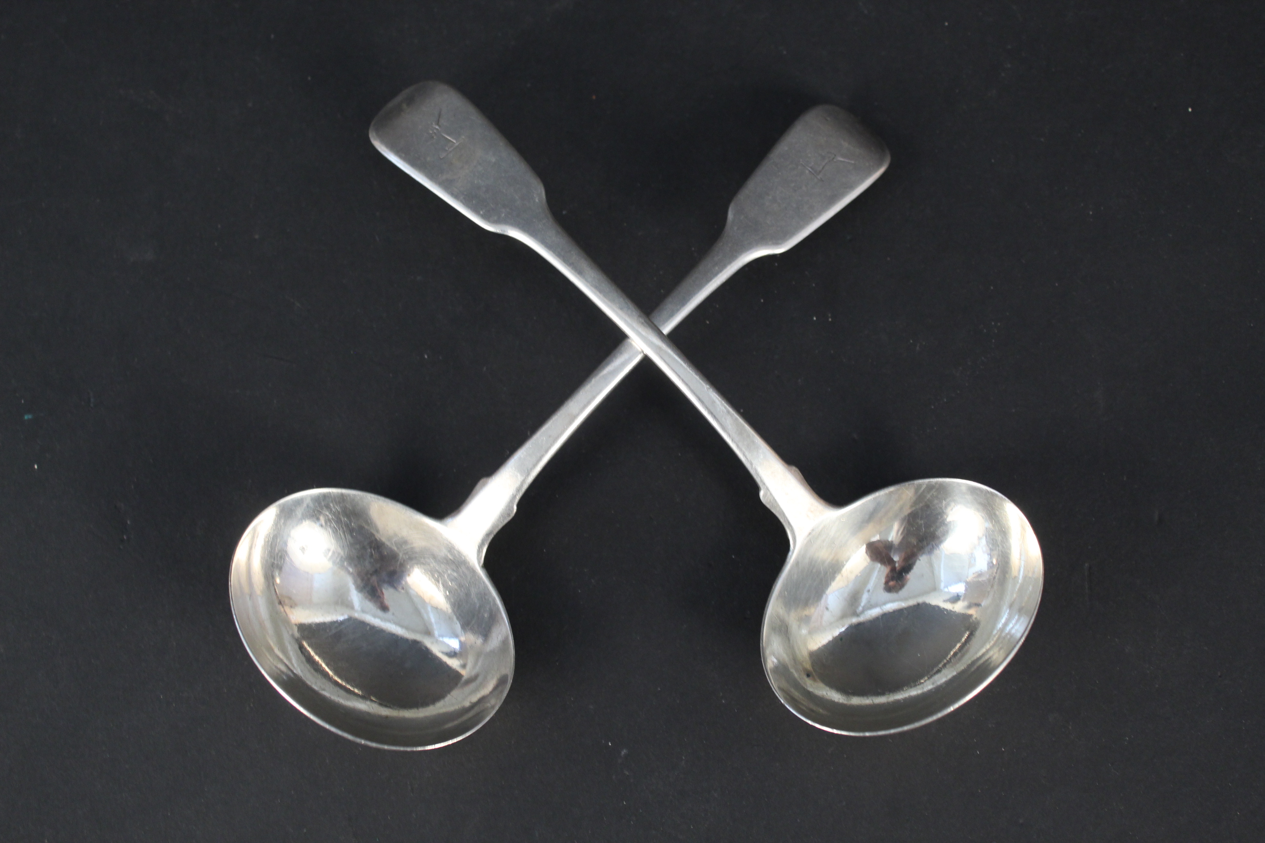 A pair of Georgian silver ladles with crested handles,