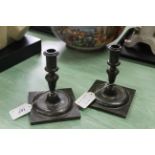 A pair of Spanish style brass or bronze candlesticks with knopped stems and wide square bases,