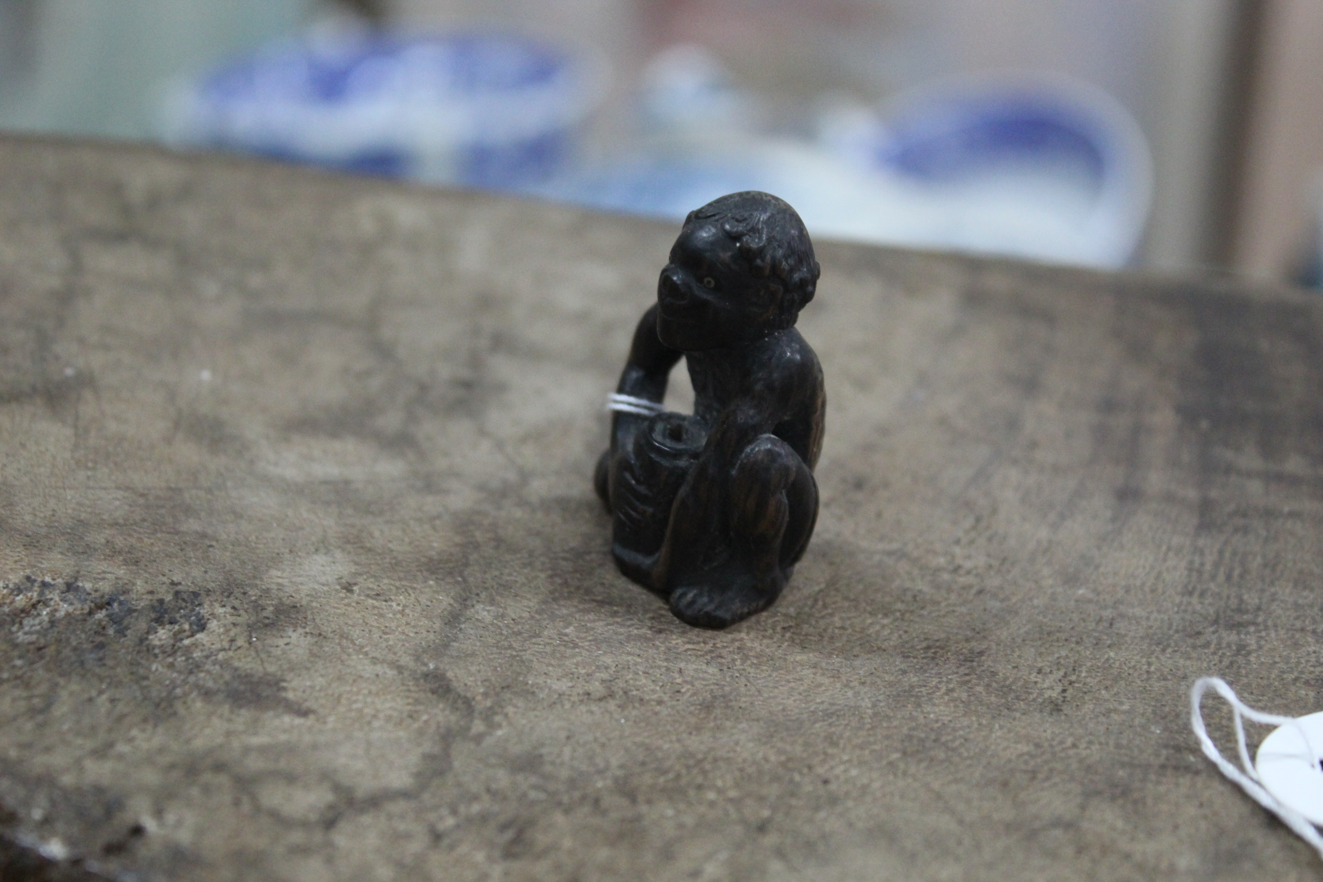 An antique carved wood netsuke on an emaciated man with pot, inset metal eyes, not signed,