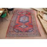 A Persian carpet with blue medallions and border on a red ground,